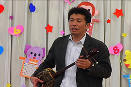 沖縄の民族楽器三線を引き語る職員