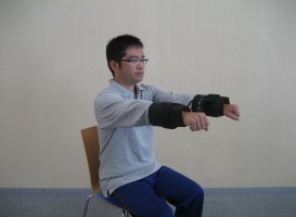 腕を前に上げる運動をしている体操のお兄さんの写真